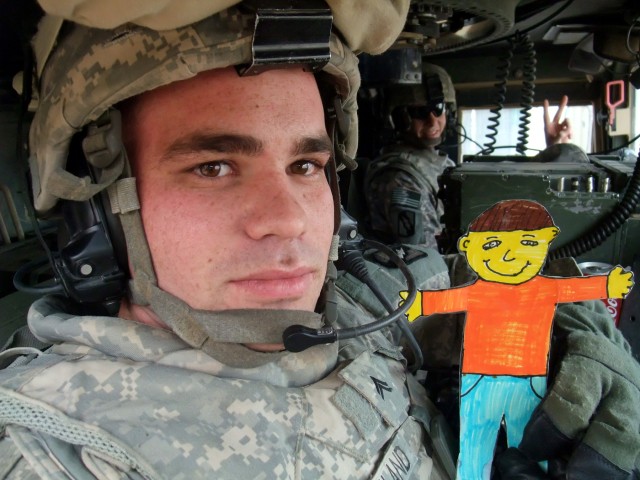 CONTINGENCY OPERATING LOCATION Q-WEST, Iraq - Cpl. Justin R. Strickland, a truck commander from Memphis, Tenn., poses in at Contingency Operating Location Q-West Jan. 13 with "Flat Stanley," a paper doll used in a pen-pal program. Third-graders with ...