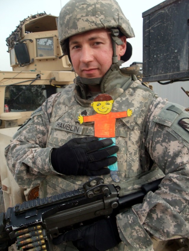 CONTINGENCY OPERATING LOCATION Q-WEST, Iraq - Sgt. James J. Hamblin, a machine gunner from Tupelo, Miss., poses in at Contingency Operating Location Q-West Jan. 13 with "Flat Stanley," a paper doll used in a pen-pal program. Third-graders with...