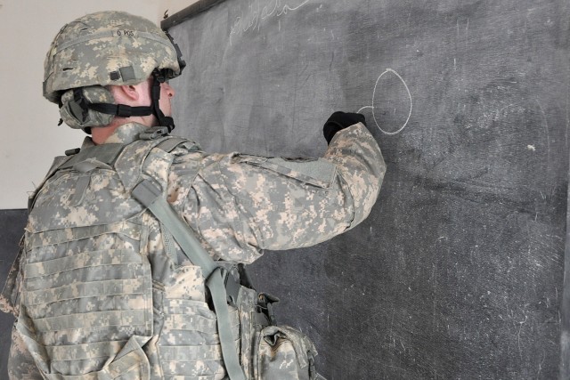 Staff Sgt. Stuart Gimble, the personal security detachment platoon sergeant, draws on the chalkboard for Iraqi students during a visit to their school Jan. 20 in the village of Jedellah Sofla, near Contingency Operating Location Q-West, Iraq....