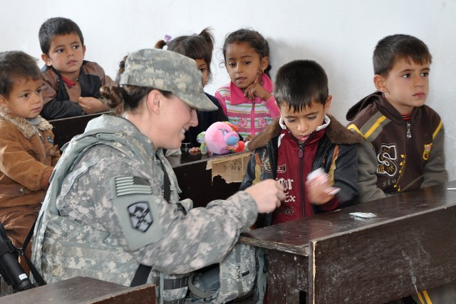 1st Lt. Meghan Flynn, an operations officer with the Special Troops Battalion, 15th Sust. Bde., hands out candy to an Iraqi student during a visit to his school Jan. 20 in the village of Jedellah Sofla, near Contingency Operating Location Q-West,...