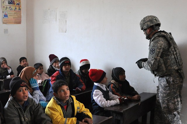 Sgt. 1st Class Israel Blanco, with the 15th Sustainment Brigade, hands out candy to Iraqi students during a visit to their school Jan. 20 in the village of Jedellah Sofla, near Contingency Operating Location Q-West, Iraq. (U.S. Army photo by Staff...