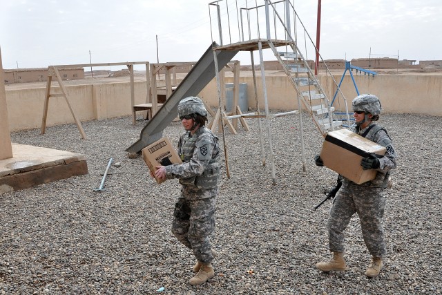 Capt. Carrie Ward, a lawyer with the 15th Sustainment Brigade, and 1st Lt. Meghan Flynn, an operations officer with the Special Troops Battalion, 15th Sust. Bde., carry school supplies to a school in Jedellah Sofla, Iraq, during a visit by the...