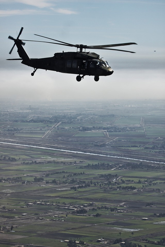 CAMP TAJI, Iraq - A UH-60 Black Hawk helicopter, from 3rd Battalion, 227th Aviation Regiment, 1st Air Cavalry Brigade, U.S. Division - Center, transports personnel to Al Asad Air Base Jan. 23. The 1st ACB maintains a task force in Al Asad to support ...