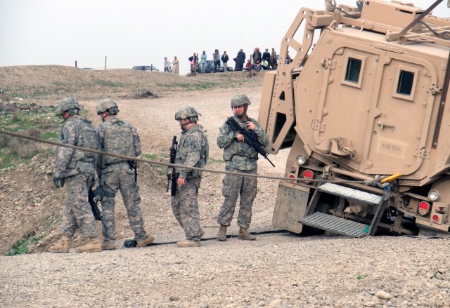 CONTINGENCY OPERATING LOCATION Q-WEST, Iraq - With villagers watching from atop a levee, the Q-West quick reaction force for recovering vehicles - manned with Soldiers from C Company, 2nd Battalion, 198th Combined Arms, 155th Brigade Combat Team,...