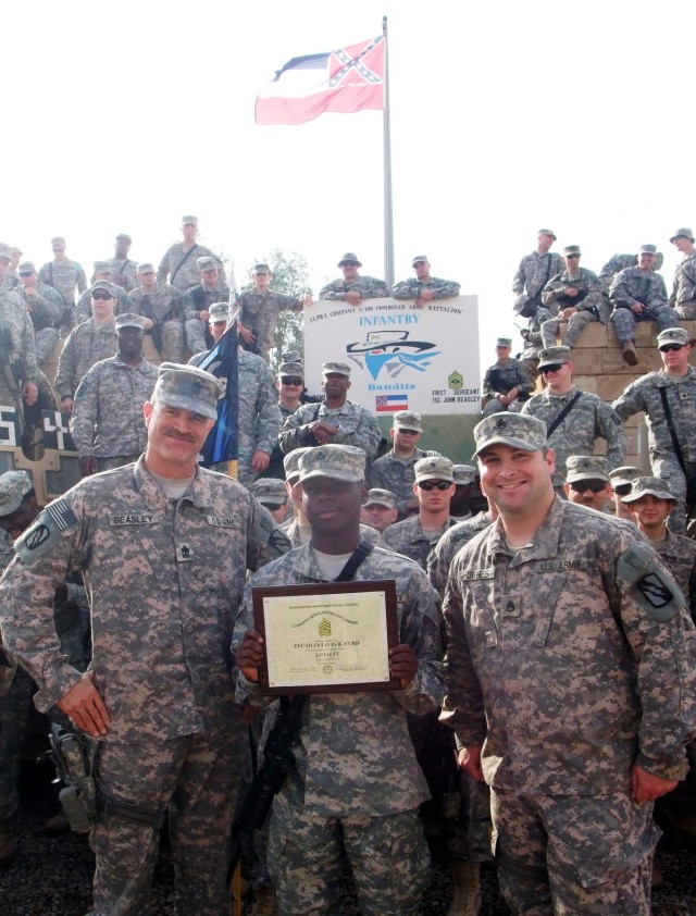 CONTINGENCY OPERATING LOCATION Q-WEST, Iraq - Pfc. Quintavis B. Byrd (center), an entry control point sentry and native of Tutwiler, Miss., holds a Command Sergeant Major award, flanked by 1st Sgt. John L. Beasley (left), a Hernando, Miss., native, a...