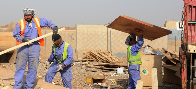 Iraqi workers, contracted by the United Mandour Company, load wood onto a truck Feb. 1 at the recycling yard at Joint Base Balad, Iraq. The pallets will be resold or reused in nearby villages. The jobs and supplies help boost the local economy and fu...
