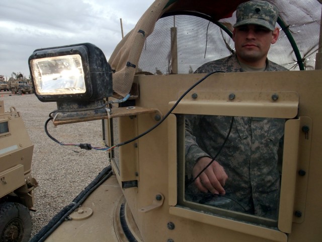 CONTINGENCY OPERATING LOCATION Q-WEST, Iraq - Spc. Robert S. Lacey, a gunner from Houston, Miss., demonstrates a spotlight mounted on his turret while performing preventative maintenance checks and services in the company area here Feb. 4. The driver...