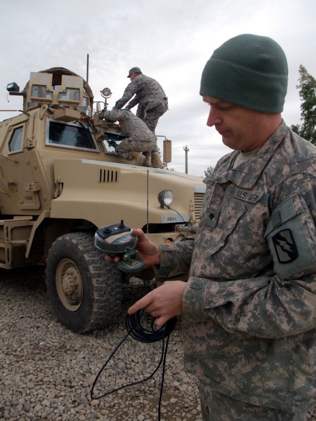CONTINGENCY OPERATING LOCATION Q-WEST, Iraq - Spc. Michael A. Boucher, a scout truck driver from Batesville, Miss., holds a remote control switch he rigged to operate a spotlight he installed in the gun turret of his Mine-Resistant,...