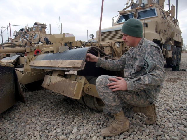 CONTINGENCY OPERATING LOCATION Q-WEST, Iraq - Spc. Michael A. Boucher, a gun truck driver from Batesville, Miss., explains how he made additional mud flaps for the Self-Protection Adaptive Roller Kit, which absorbs bomb damage, shielding the vehicle ...