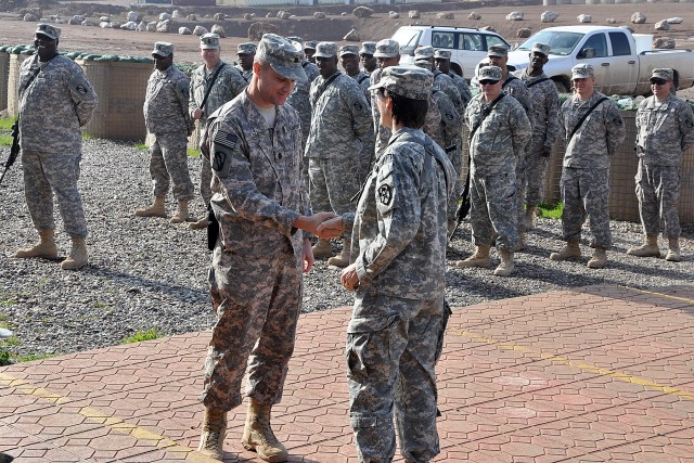 Lt. Col. William B. Smith Jr., the outgoing Contingency Operating Location Q-West mayor, and Lt. Col. Paula Lodi, the commander of the Special Troops Battalion, 15th Sustainment Brigade, 13th Sustainment Command (Expeditionary), exchange coins to sym...