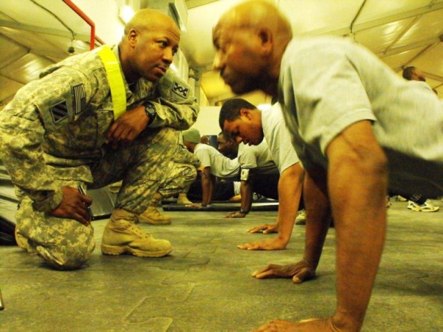 CAMP LIBERTY, Iraq-Staff Sgt. Frederick McNeil, of Liberty, Miss., grades Staff Sgt. Larry Walker from Palm Harbor, Fla., during the push-up event of the army physical fitness test.  This is the first test given while in theater for the 296th Transpo...