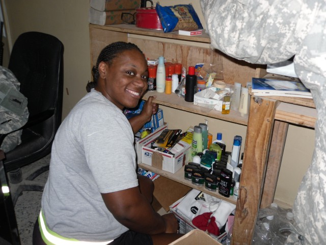 Spc. Selecia Rakestrau, an admin clerk in the 716th Quartermaster Company and Jersey City, N.J., native, helps to organize some of the items on the free-for-all shelf in the company tactical operation center.  (U.S. Army photo by 1st Lt. Herbert...