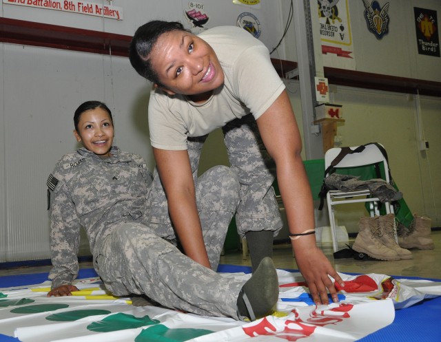 Cpl. Rebecca Rojas [left] from Bakersfield, Calif., and Spc. Teasia Jackson from Virginia Beach, Va., both supply specialists with 204th Military Police Company, play an hour-long game of twister during a pre-Super Bowl party in the dining...