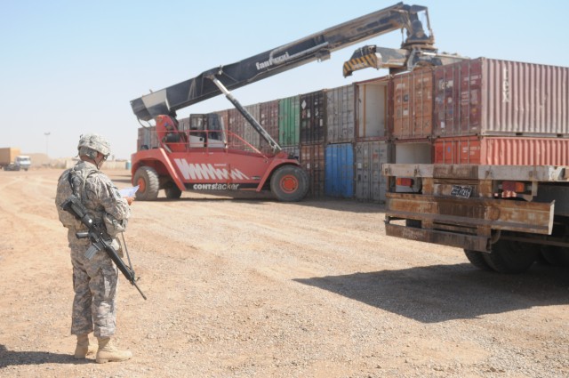 A Soldier looks on as a rough terrain container handler picks up an empty container and loads it on a flatbed truck at the Receiving and Shipping Point yard at Joint Base Balad, Iraq. The CRSP will be relocated to an expanded location, tripling its c...