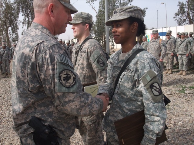 CONTINGENCY OPERATING LOCATION Q-WEST, Iraq - Command Sgt. Major Perry Campbell (left), of Senatobia, Miss., bestows a brigade commander deployment coin on Sgt. Victoria M. Moffett, of Collins, Miss., during a ceremony here Feb. 15. The ceremony...