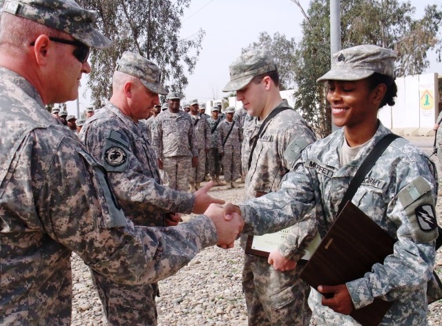CONTINGENCY OPERATING LOCATION Q-WEST, Iraq - 1st Sgt. Troy D. Scott (left foreground), of Pearl, Miss., awards a command sergeant major's award to Sgt. Victoria M. Moffett (right foreground), of Collins, Miss., while Command Sgt. Maj. Perry...