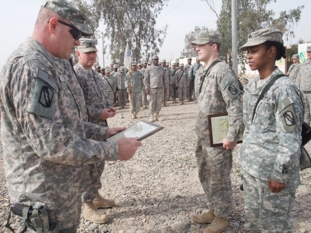 CONTINGENCY OPERATING LOCATION Q-WEST, Iraq - 1st Sgt. Troy D. Scott (left foreground), of Pearl, Miss., reads a command sergeant major's award before presenting it to Sgt. Victoria M. Moffett (right foreground), of Collins, Miss., during a...