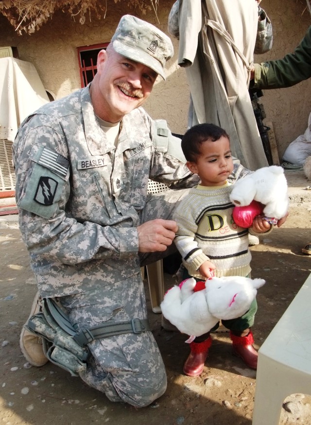 CONTINGENCY OPERATING LOCATION Q-WEST, Iraq -1st Sgt. John L. Beasely, of Hernando, Miss., poses with Muhammed Abrahim, the youngest child of Khalil Abrahim, a wheat and sheep farmer near Al Qayarrah, when Beasley and other members of his unit brough...