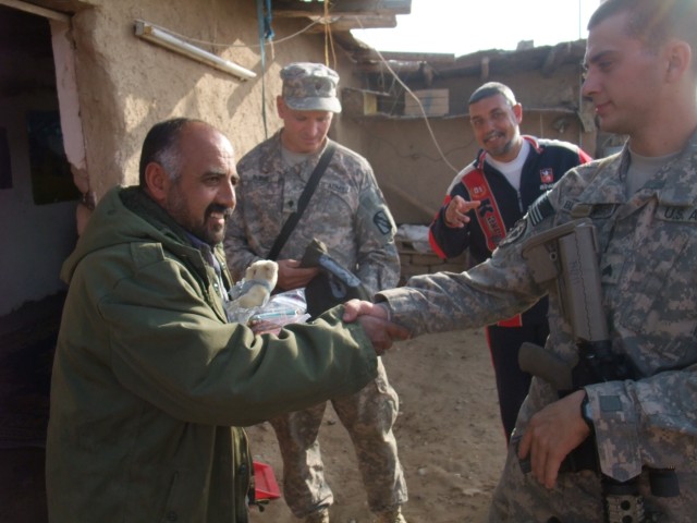 CONTINGENCY OPERATING LOCATION Q-WEST, Iraq -Khalil Abrahim (left), a wheat and sheep farmer near Al Qayarrah, shakes hands with Sgt. Seth A. Bloodworth, a truck commander from Lake Cormorant, Miss., while Spc. Daniel Burke, a gun truck driver from A...