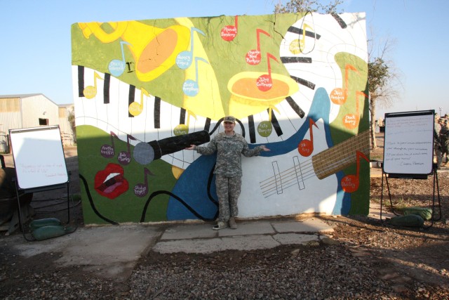 Spc. Nicole Day, a Carrollton, Ohio, native with the 1483rd Transportation Company, 541st Combat Sustainment Support Battalion, 15th Sustainment Brigade, 13th Sustainment Command (Expeditionary), poses with her finished mural. Day sketched and...