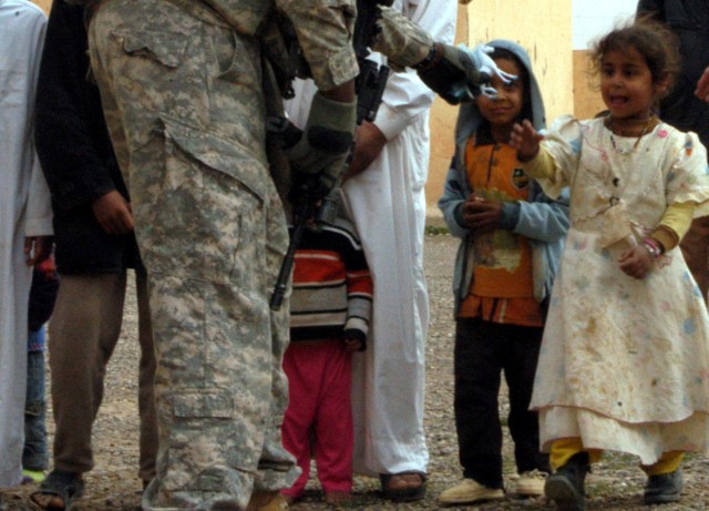 CONTINGENCY OPERATING LOCATION Q-WEST, Iraq - A young girl accepts a toy horse from a Mississippi Guardsman during a humanitarian mission in Jedallah Anuk, a small village near Q-West, Feb. 1. Members of A Company, 2nd Battalion, 198th Combined...