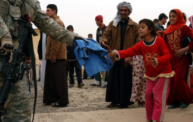 CONTINGENCY OPERATING LOCATION Q-WEST, Iraq - A young girl accepts a T-shirt from a Mississippi Guardsman during a humanitarian mission in Jedallah Anuk, a small village near Q-West, Feb. 1. Members of A Company, 2nd Battalion, 198th Combined...