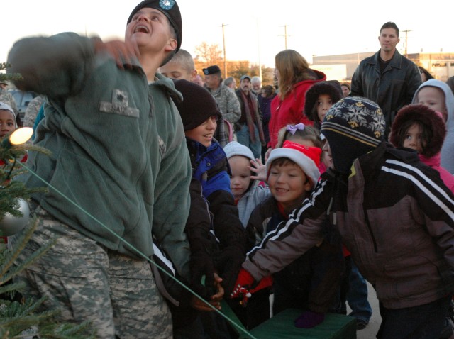Lt. Col. Saiz, rear detachment commander, 15th Sustainment Brigade, 13th Sustainment Command (Expeditionary) and junior "Wagonmasters" light the way for Santa's arrival to the "Wagonmasters" Tree Lighting Ceremony that took place, here Dec....