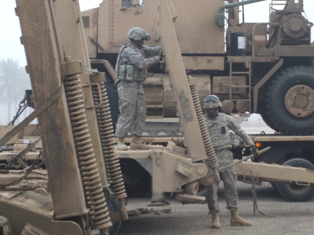 CAMP LIBERTY, Iraq-Sgt. Lyle Thurmond, a native of Washington D.C., and Spc. Harold James of Savannah, Ga., secure a loading ramp in the up-right position of a heavy equipment transporter after unloading a vehicle from the trailer while on...