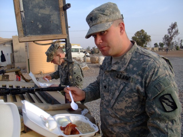 CONTINGENCY OPERATING LOCATION Q-WEST, Iraq - Spc. Andrew D. Cantler (right), a gun truck driver from Memphis, Tenn., and Spc. Brandon L. Pettit, a gunner from Clarksdale, Miss., eat a quick breakfast on the hood of their gun truck before a...