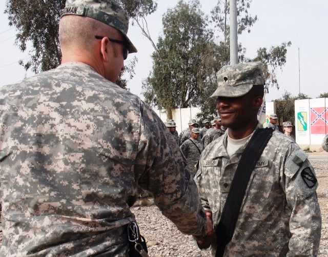 CONTINGENCY OPERATING LOCATION Q-WEST, Iraq - Spc. Tobias Butler (right), a gunner from Indianola, Miss., serving with C Company, 2nd Battalion, 198th Combined Arms, 155th Brigade Combat Team, out of Oxford and Indianola, Miss., receives a...