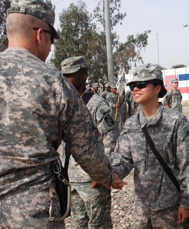 CONTINGENCY OPERATING LOCATION Q-WEST, Iraq - Sgt. Gerrelaine Alcordo (right), a truck commander from New York City serving with A Company, 106th Brigade Support Battalion, out of Magee, Miss., receives a deployment coin from Lt. Col. Kerry...