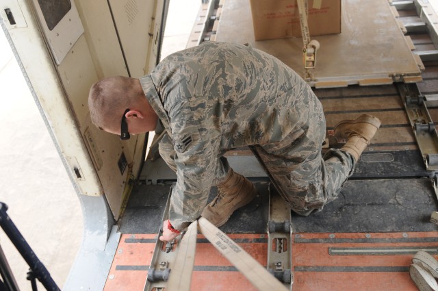 Airman 1st class Brett Lambert, an air transport and Sherpa operations coordinator with the 56th Movement Control Team, 49th Transportation Battalion, 13th Sustainment Command (Expeditionary) and a San Jose, Calif., native, tightens the straps to sec...