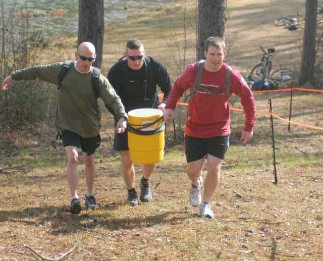 Keith Moser, Thomas Sheehan and Andrew Webber carry a full cooler of water using rope and boards Saturday at the Adventure Race at Kings Pond. They couldn’t drop more than four inches of water and couldn’t touch the handles or nozzle. This was...