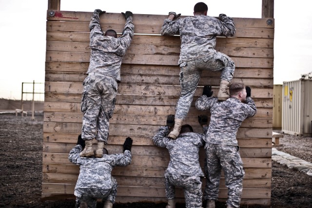 CAMP TAJI, Iraq - Trying to get a quick time through the obstacle course, Soldiers from Company F, 3rd Battalion, 227th Aviation Regiment, 1st Air Cavalry Brigade, 1st Cavalry Division, U.S. Division-Center, form "steps" with their bodies to get over...