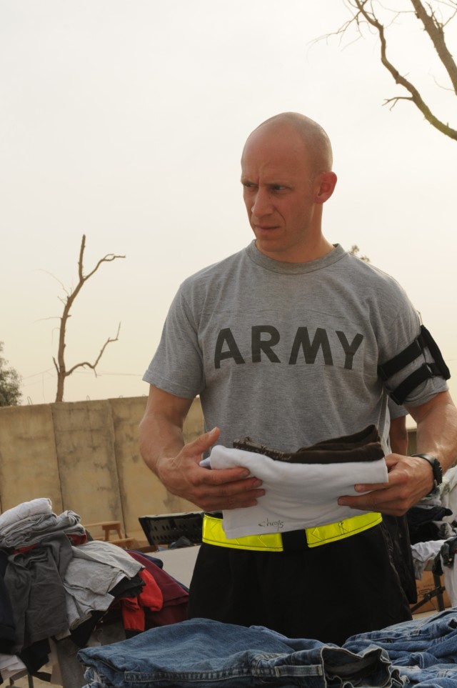 Staff Sgt. Brent J. Allred, a supply sergeant with the 3666th Support Maintenance Company, 541st Combat Sustainment Support Battalion, 15th Sustainment Brigade, 13th Sustainment Command (Expeditionary), folds clothes to be given to local Iraqi childr...