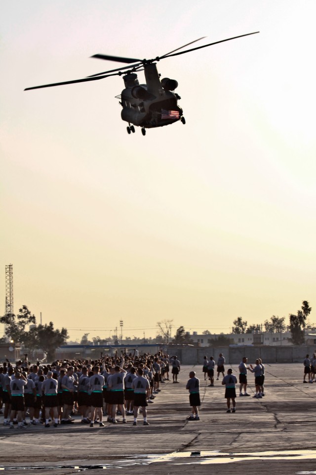 CAMP TAJI, Iraq - Before the noncommissioned officers of 1st Air Cavalry Brigade, 1st Cavalry Division, U.S. Division - Center, begin a morning run, a CH-47F Chinook helicopter from Company B, 2nd Battalion, 227th Aviation Regiment, 1st ACB, passes b...