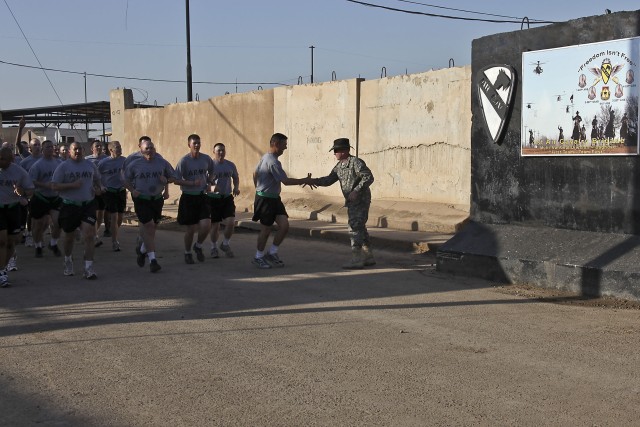 CAMP TAJI, Iraq - Leading his noncommissioned officers on a run to build esprit de corps, Command Sgt. Maj. Glen Vela, from Dallas, the command sergeant major of 1st Air Cavalry Brigade, 1st Cavalry Division, U.S. Division - Center, shakes hands with...