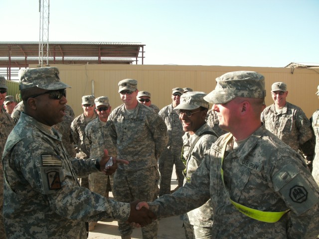 Cmd. Sgt. Maj. Melvin Rutledge, the 264th Combat Sustainment Support Battalion senior noncommissioned officer, shakes hand with Spc. James Elledge, with the 1083rd Transportation Company, and awards him for his outstanding performance on missions...