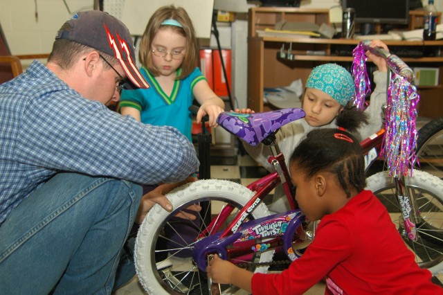 FORT WAINWRIGHT, Alaska - Dan Degrave, Automotive Skills Center worker, teaches his group how to assemble a bicycle during the EDGE! program's "Pedal On" class Tuesday at the Automotive Skills Center. Annelisa Walter (left), 9, daughter of Elisabeth ...