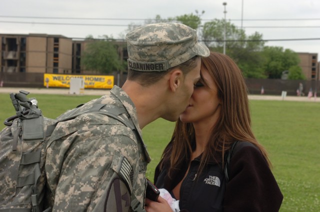 FORT HOOD, Texas-Capt. Logan Cloaninger (left), of 1st Battalion, 227th Aviation Regiment, 1st Air Cavalry Brigade, 1st Cavalry Division, greets girlfriend Christine Holder with a kiss after a welcome home ceremony at Cooper Field, April 19. Holder t...