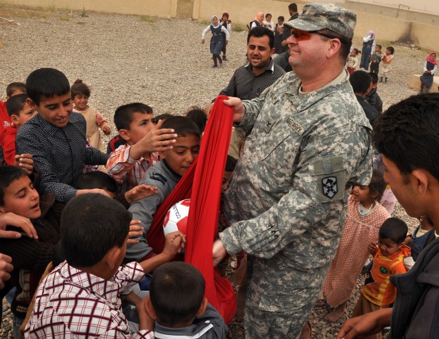 Col. Larry Phelps, a Greenville, Ala., native, and commander of 15th Sustainment Brigade, 13th Sustainment Command (Expeditionary), passes out soccer balls to children during a visit to the school here April 12. (U.S. Army photo by Staff Sgt....
