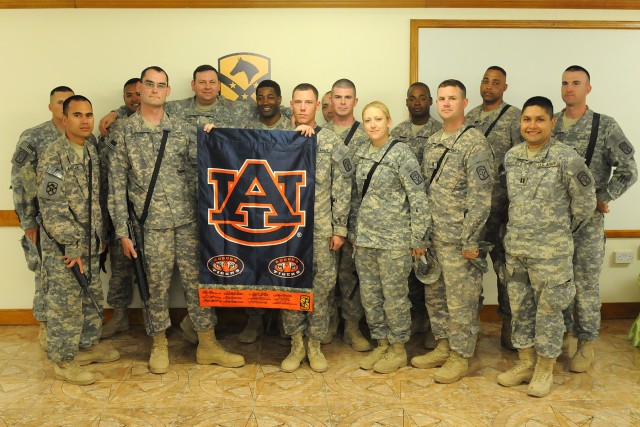 Members of the 40th Transportation Company, Special Troops Battalion, 15th Sustainment Brigade, pose with an Auburn University flag signed by Auburn faculty members, local politicians, U.S. Senators and the governor of Alabama during its...