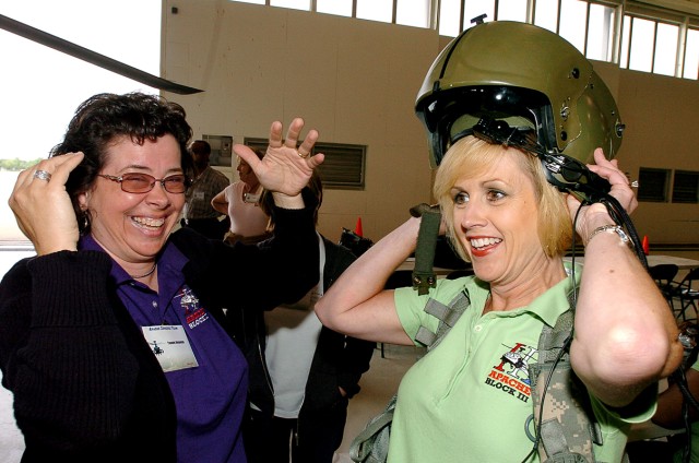 FORT HOOD, Texas-Yvonne Reynolds (left), an Army Contracting Command contracting officer, of Huntsville, Ala., laughs at the tight fit when Lisa Stangle, AMCOM's director of Apache Contracts, tries on an Apache pilot's helmet during a site visit,...