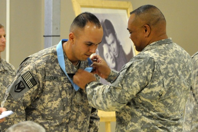 Command Sgt. Maj. Arthur L. Coleman, the III Corps senior noncommissioned officer, places the Sergeant Audie Murphy Club medallion around the neck of Staff Sgt. Mario Curtis, a shop foreman with the 1st Maintenance Company, 260th Combat Sustainment S...