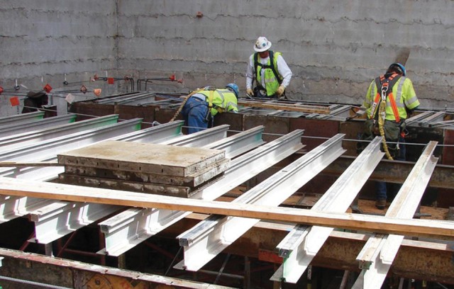 Workers place roof extension beams 