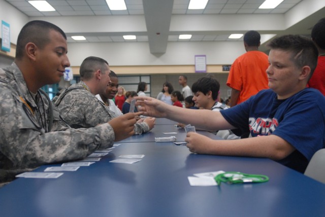 FORT HOOD, Texas - Chicago native, Spc. Alejandro Alvarez (left), a scout assigned to Troop C, 1st Squadron, 7th Cavalry Regiment, 1st Brigade Combat Team, 1st Cavalry Division, plays a card game with a sixth grade student at the Palo Alto Middle...