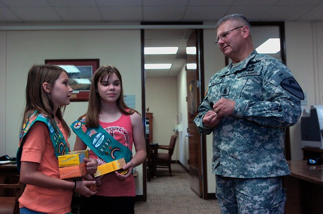 FORT HOOD, Texas - Madison Gray (left) and Gillian Herman, Girl Scouts with Girl Scout Troop 8737, from Frisco, Texas, receive a challenge coin from Command Sgt. Maj. Rory Malloy, 1st Cav. Div., for donating 116 boxes of Girl Scout cookies to the...