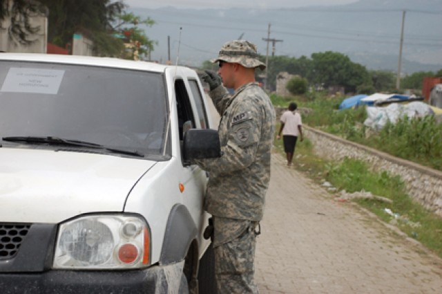 Sgt. Nathan J. Kron instructs a driver for Task Force Kout Men ("helping hands") where to park while providing force protection during base camp construction near Gonaives, Haiti, about 95 miles north of Port au Prince. Kron was part of a group of...