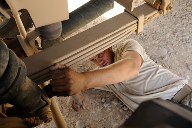 Working in tight quarters, Sgt. Orlando Boneshirt, a light-wheeled vehicle mechanic for Headquarters and Headquarters Company, Division Special Troops Battalion, 3rd Infantry Division, tightens the retaining nut onto the mounting bolt for the...