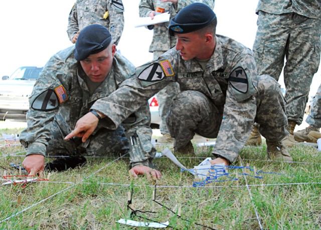 FORT HOOD, Texas- Sgt. Seth Eaton (right) and Spc. Nicholas Lemon, both forward observers with Headquarters and Headquarters Company, 2nd Brigade Combat Team, 1st Cavalry Division, look at features of a sand table while setting it up for forward...